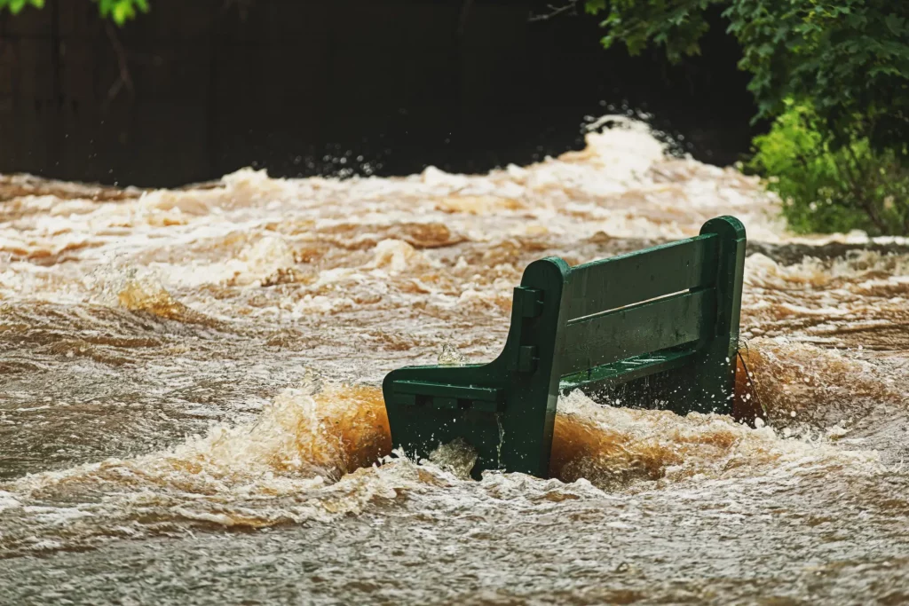 A public bench engulfed by raging floodwaters, symbolizing the impact of water-related risks on communities.