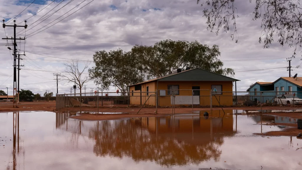Flooded house surrounded by flood waters, symbolizing the destructive impact of flooding on homes and infrastructure.